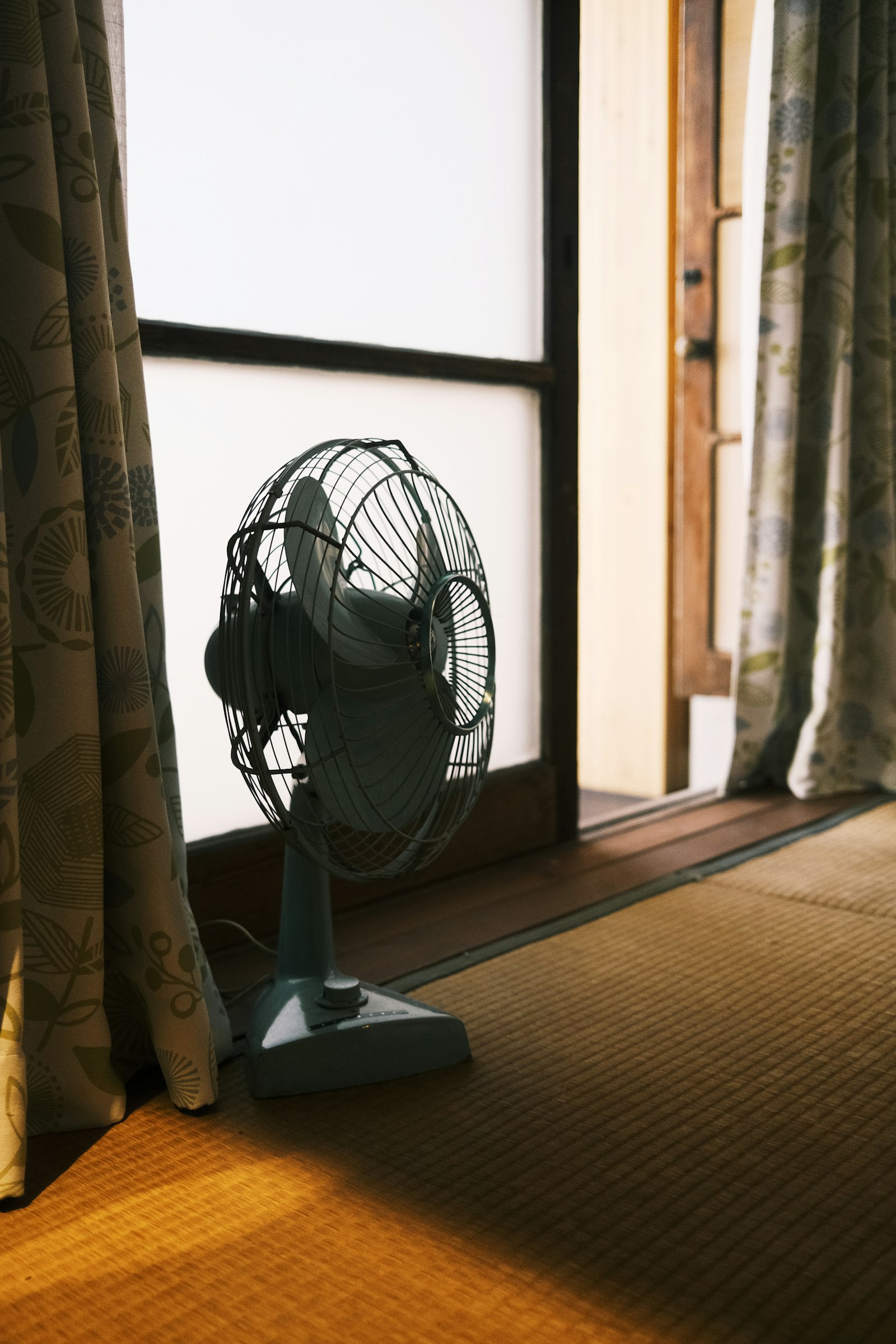 障子窓のそばの畳に置かれた、レトロな扇風機