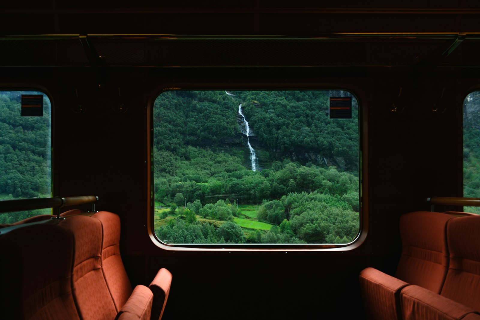 走る列車の窓越しに見える、緑の山肌と細い滝