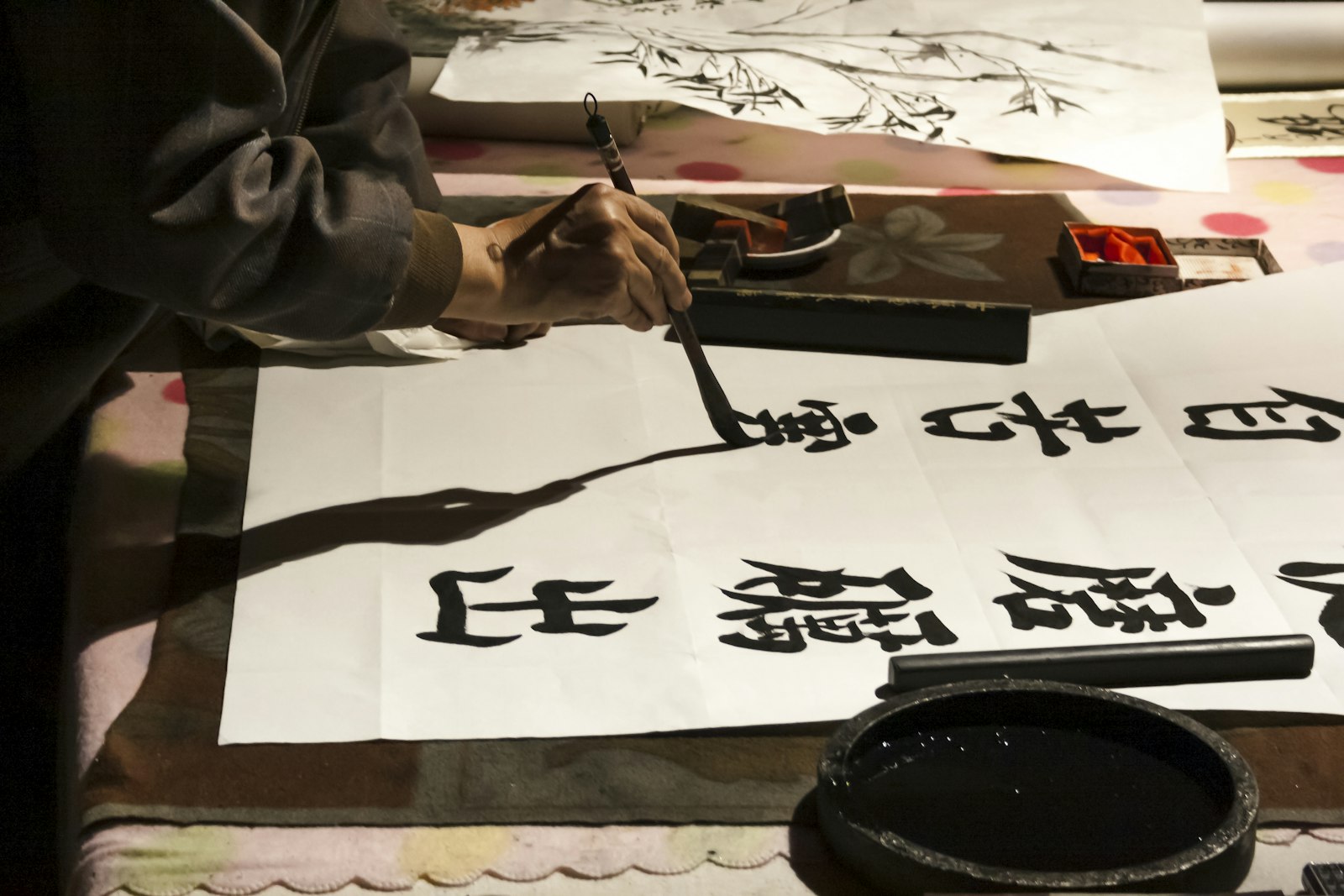 筆と硯を前に、紙へ文字を書きつける手元